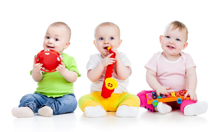 2 små babier sidder med musik instrumenter og smiler 